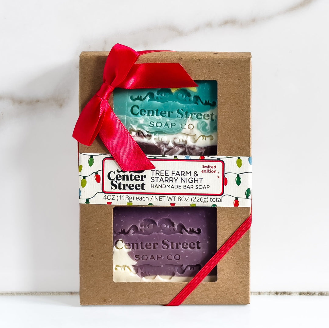 A gift set of two handmade bar soaps by Center Street Soap Co. in a brown kraft paper box with a red ribbon bow.